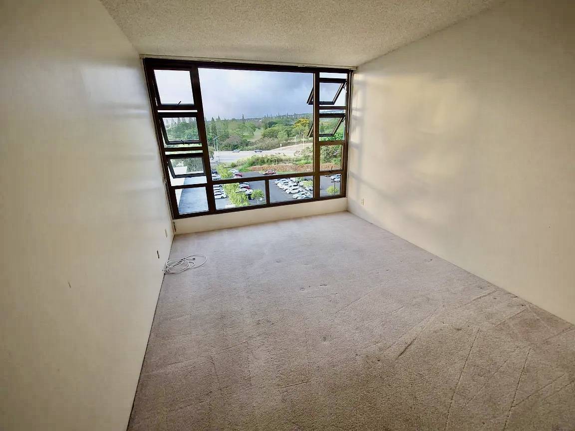 A room with a large window overlooking a parking lot.